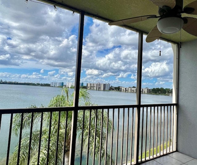 unfurnished sunroom featuring ceiling fan and a water view