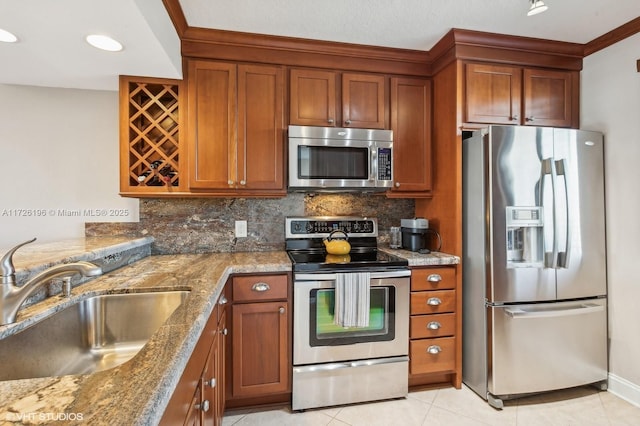 kitchen with backsplash, sink, appliances with stainless steel finishes, light tile patterned floors, and stone countertops