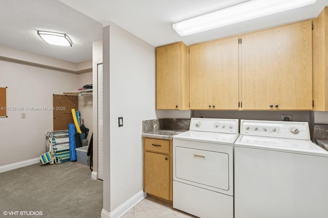 laundry area featuring light colored carpet, washer and dryer, a textured ceiling, and cabinets