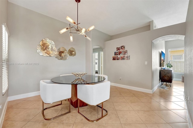 tiled dining space featuring an inviting chandelier and vaulted ceiling