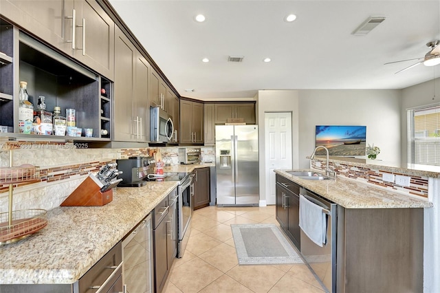 kitchen featuring sink, decorative backsplash, light stone counters, and appliances with stainless steel finishes