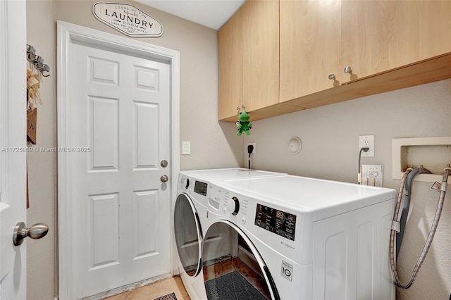 clothes washing area with washing machine and clothes dryer, light tile patterned floors, and cabinets