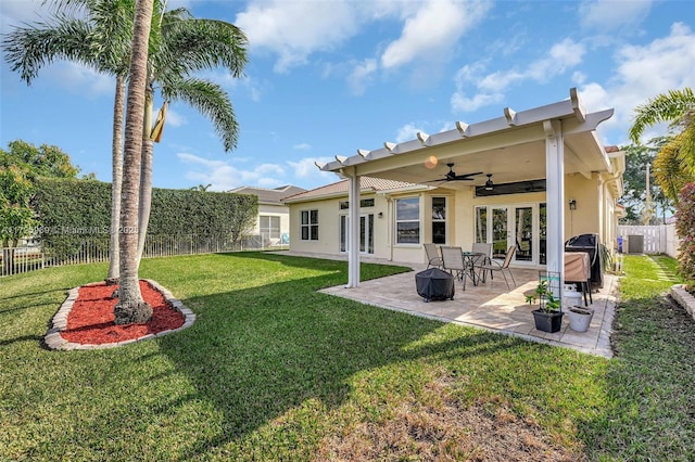 rear view of property with ceiling fan, french doors, a patio, and a lawn