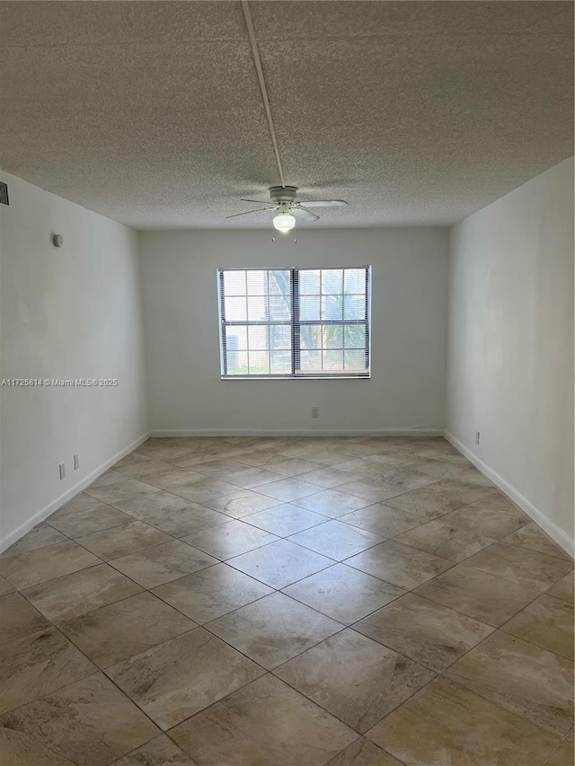 unfurnished room with visible vents, ceiling fan, a textured ceiling, and baseboards