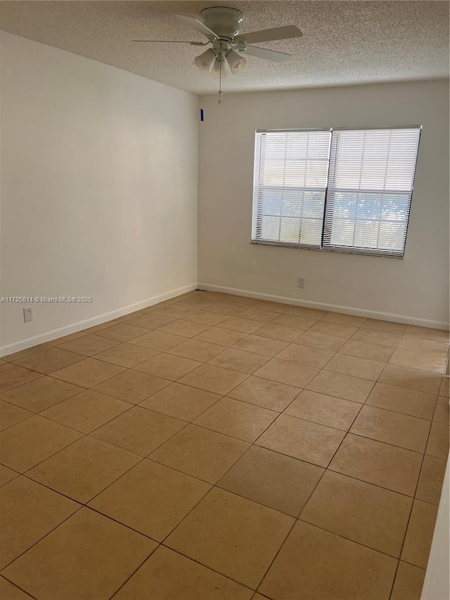 spare room featuring a ceiling fan, a healthy amount of sunlight, a textured ceiling, and baseboards