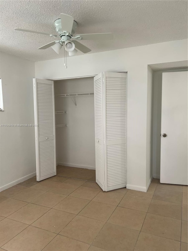 unfurnished bedroom with light tile patterned floors, a ceiling fan, baseboards, and a textured ceiling