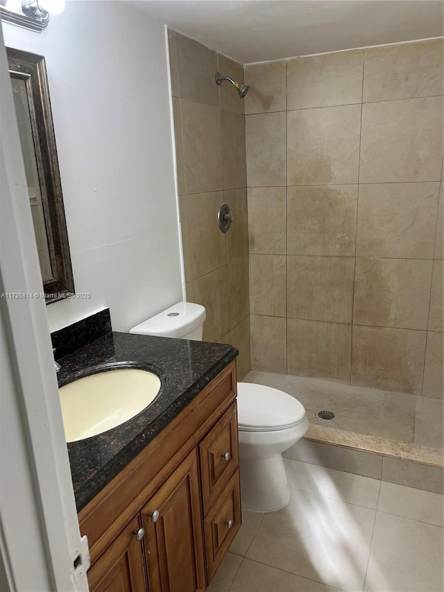 full bathroom with tiled shower, vanity, toilet, and tile patterned floors