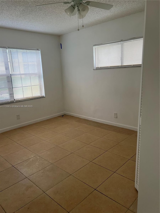 spare room with a textured ceiling, ceiling fan, baseboards, and a healthy amount of sunlight