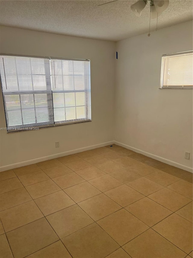 empty room with a healthy amount of sunlight, baseboards, and a textured ceiling