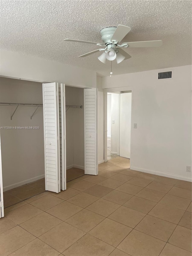 unfurnished bedroom featuring baseboards, visible vents, a ceiling fan, a textured ceiling, and multiple closets