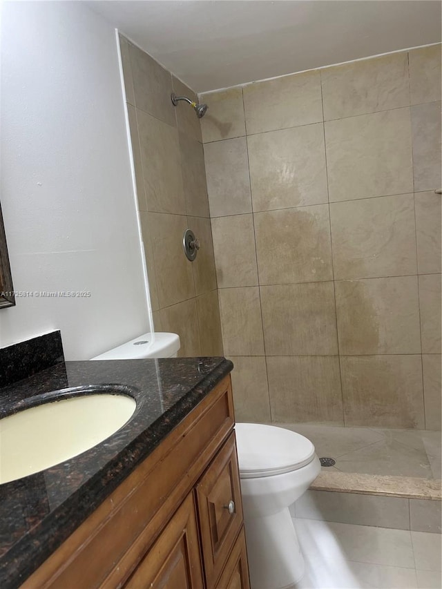 bathroom featuring toilet, tiled shower, and vanity