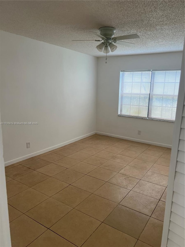 empty room with a textured ceiling, a ceiling fan, and baseboards