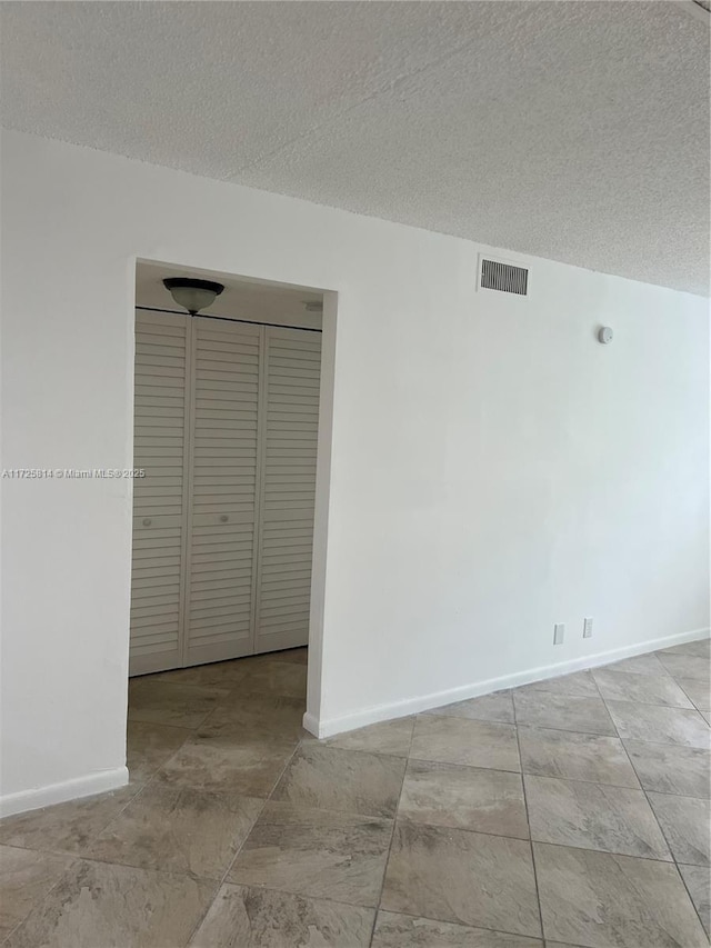 unfurnished room featuring visible vents, a textured ceiling, and baseboards