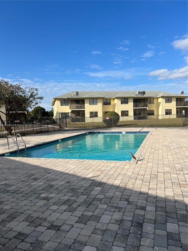 pool with a patio area and fence