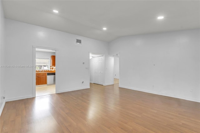 unfurnished room with light wood-type flooring and vaulted ceiling