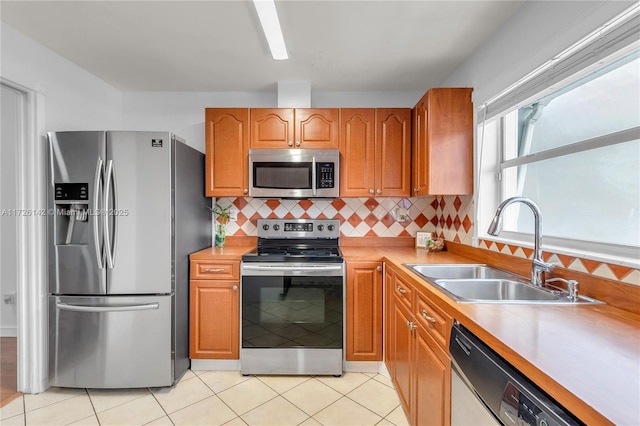 kitchen with appliances with stainless steel finishes, decorative backsplash, light tile patterned flooring, and sink