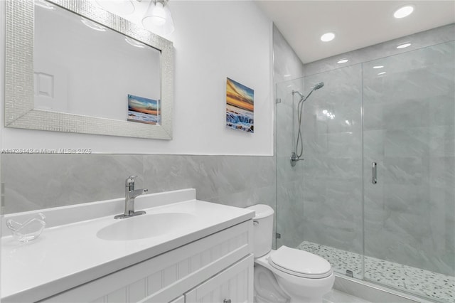 bathroom with toilet, walk in shower, vanity, and tile walls