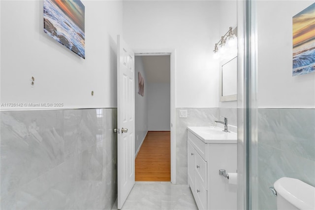 bathroom with tile walls, toilet, and vanity