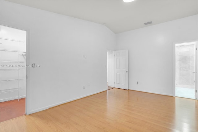 unfurnished room featuring lofted ceiling and light hardwood / wood-style flooring