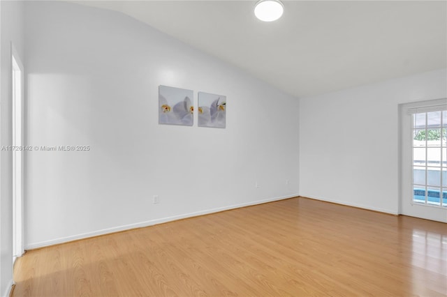 spare room with lofted ceiling and light hardwood / wood-style floors