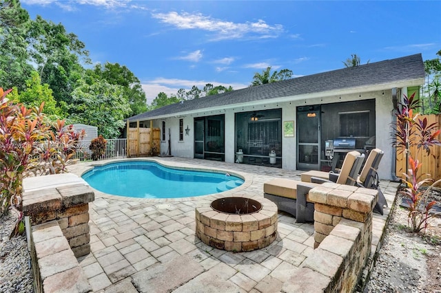 view of swimming pool featuring ceiling fan, an outdoor fire pit, and a patio area