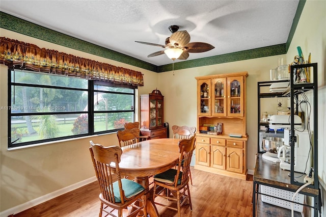 dining area with a textured ceiling, ceiling fan, and light hardwood / wood-style flooring