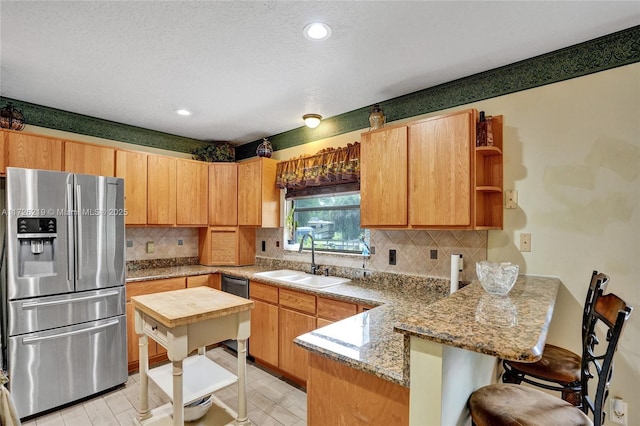 kitchen with stainless steel appliances, sink, kitchen peninsula, a breakfast bar area, and backsplash