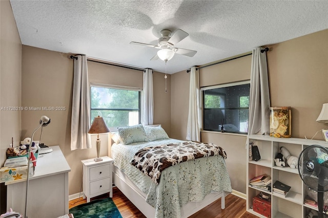 bedroom with ceiling fan, a textured ceiling, and dark hardwood / wood-style floors