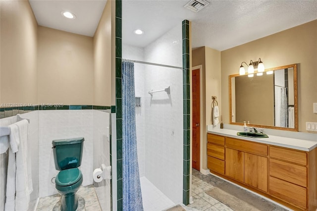 bathroom with tile walls, tile patterned floors, vanity, and curtained shower