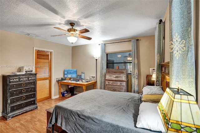 bedroom featuring ceiling fan, light wood-type flooring, and a textured ceiling