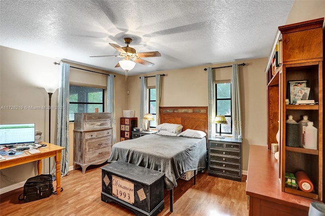 bedroom featuring ceiling fan, light hardwood / wood-style floors, and a textured ceiling