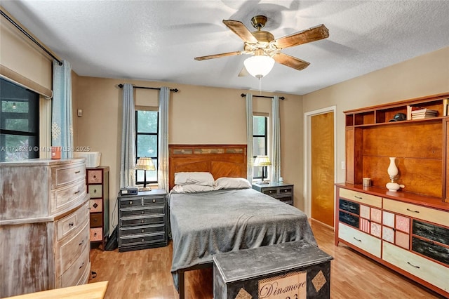 bedroom featuring ceiling fan, light hardwood / wood-style floors, a closet, and a textured ceiling