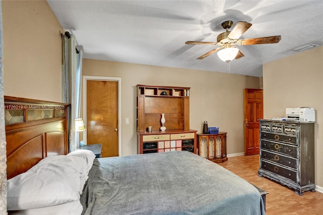 bedroom with a textured ceiling, ceiling fan, and light hardwood / wood-style flooring