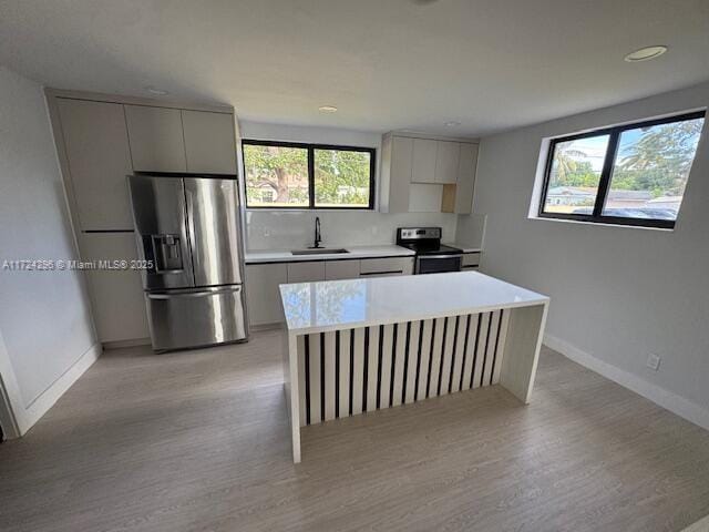 kitchen with appliances with stainless steel finishes, light hardwood / wood-style floors, gray cabinets, and sink