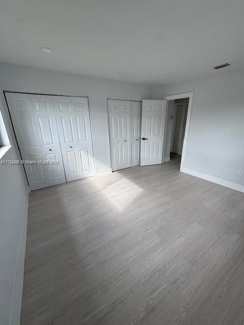 unfurnished bedroom with two closets and hardwood / wood-style flooring