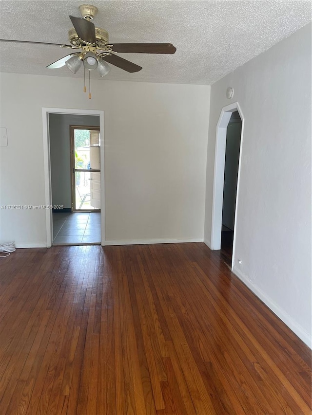 empty room with ceiling fan, a textured ceiling, and dark hardwood / wood-style floors