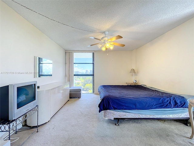 bedroom with ceiling fan, light colored carpet, and a textured ceiling