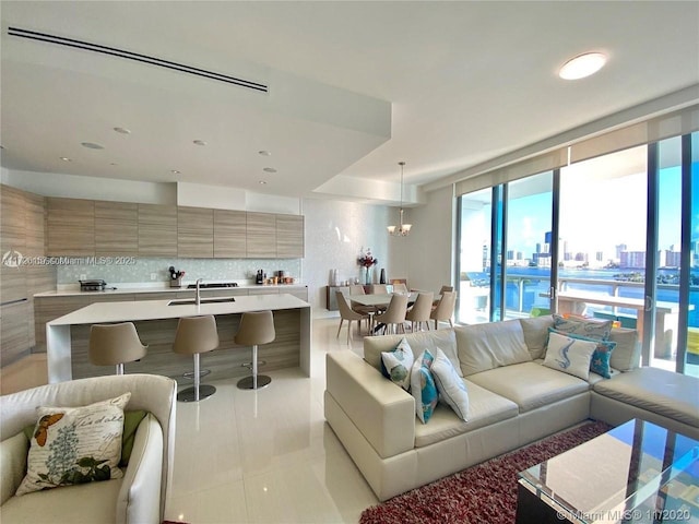 living room featuring sink, an inviting chandelier, and light tile patterned flooring