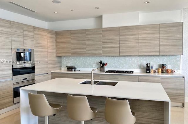 kitchen with a kitchen island with sink, backsplash, a kitchen breakfast bar, and appliances with stainless steel finishes