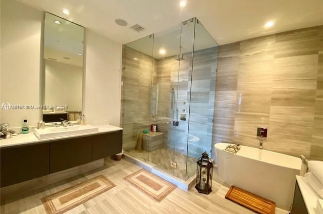 bathroom with tile walls, separate shower and tub, and vanity