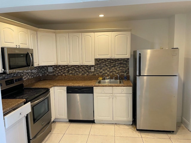 kitchen with stainless steel appliances, light tile patterned flooring, white cabinetry, and sink