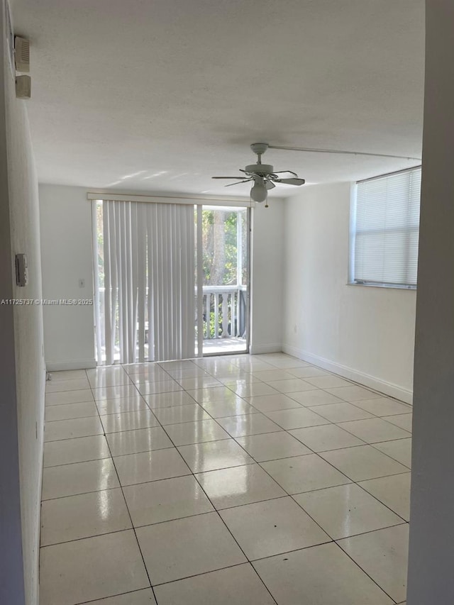 spare room with ceiling fan and light tile patterned floors