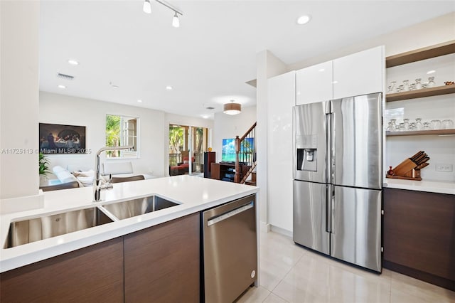 kitchen featuring sink, light tile patterned floors, stainless steel appliances, and white cabinets