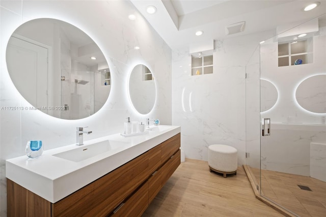 bathroom featuring a shower with shower door, vanity, tile walls, and wood-type flooring