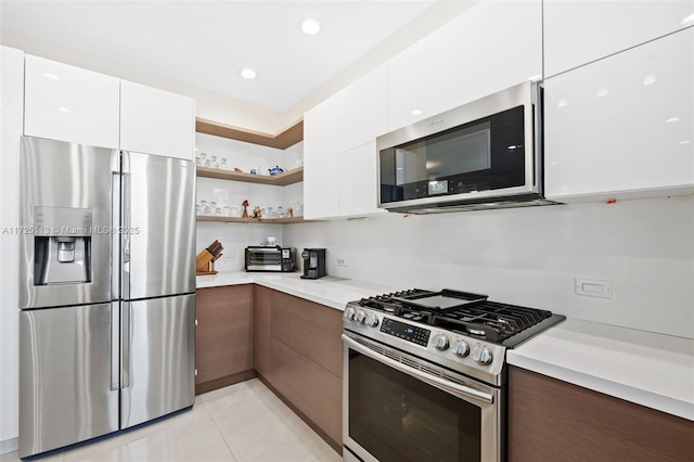 kitchen featuring light tile patterned floors, appliances with stainless steel finishes, and white cabinets