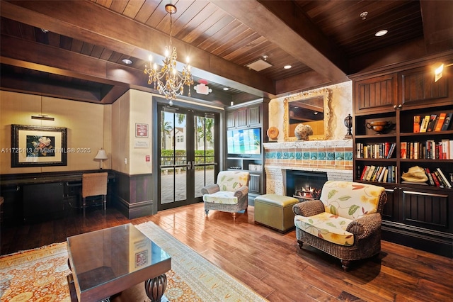 living area with wood ceiling, hardwood / wood-style floors, beam ceiling, a large fireplace, and french doors