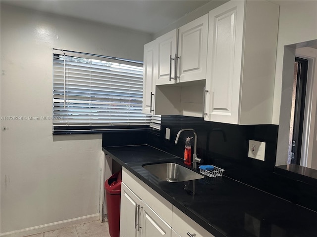 kitchen with light tile patterned floors, sink, and white cabinets