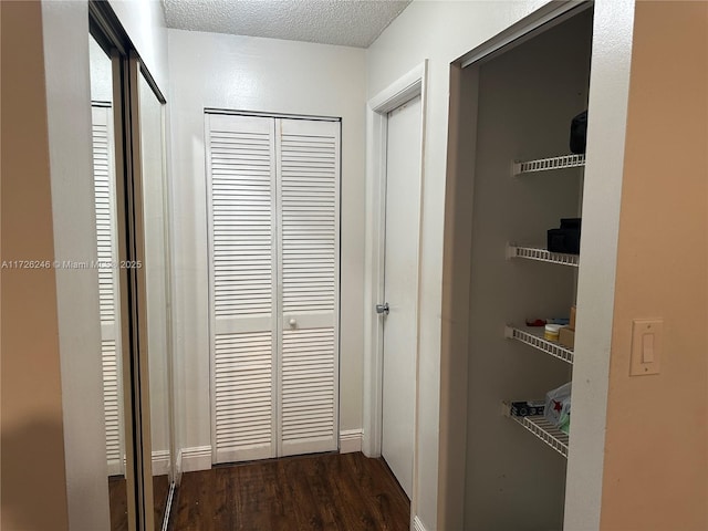 corridor with dark hardwood / wood-style flooring and a textured ceiling