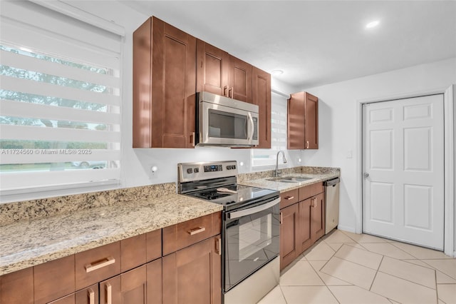 kitchen featuring appliances with stainless steel finishes, light stone countertops, sink, and light tile patterned floors