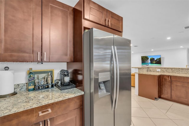 kitchen featuring light stone countertops, light tile patterned flooring, and stainless steel fridge